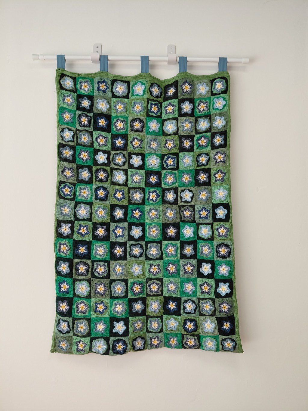 A crochet quilt with blue and green squares.