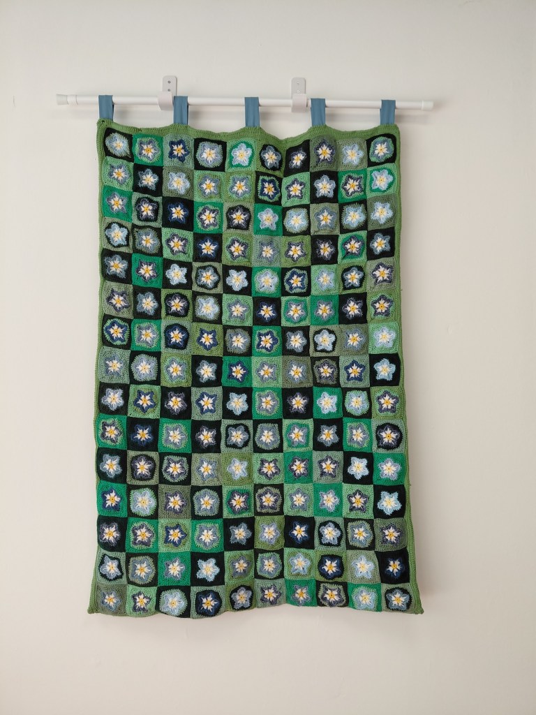 A crochet quilt with blue and green squares.